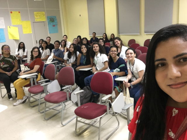 estudantes sentados de frente a computadores e os professores na frente explicando o conteúdo.o.